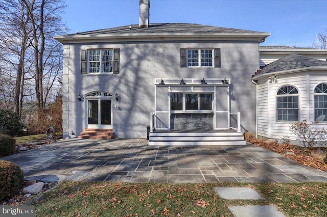 rear view of property featuring entry steps, brick siding, and a patio