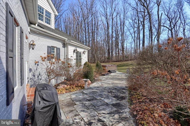 view of side of home featuring brick siding and a patio