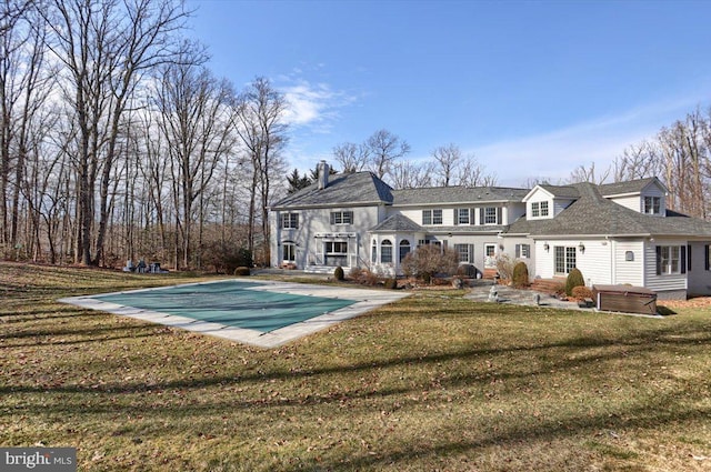 rear view of property with a yard and a covered pool