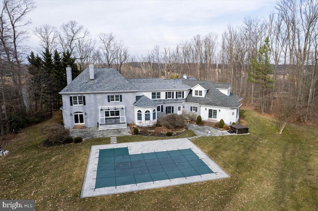 back of property with a patio area, a lawn, a chimney, and a covered pool