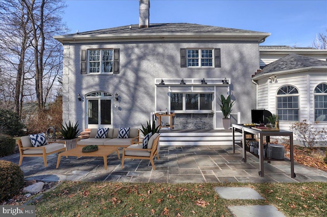 rear view of property with central air condition unit, a patio area, an outdoor hangout area, and brick siding