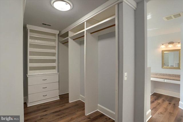 walk in closet featuring visible vents, dark wood-type flooring, and built in study area