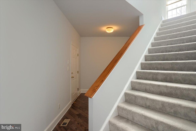 stairway with visible vents, baseboards, and wood finished floors