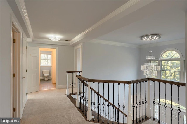 hallway featuring ornamental molding, a chandelier, carpet flooring, and an upstairs landing