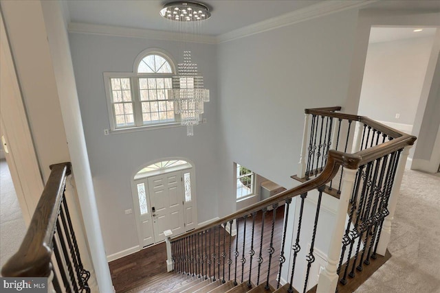 entrance foyer featuring a chandelier, baseboards, a towering ceiling, and crown molding