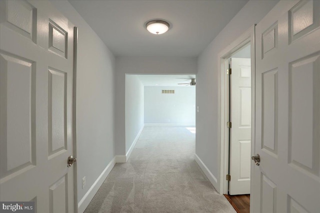 hall with carpet, visible vents, and baseboards