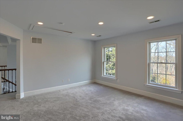 unfurnished room with baseboards, carpet, visible vents, and attic access