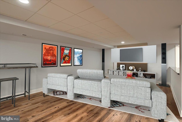 home theater featuring a drop ceiling, visible vents, baseboards, and wood finished floors