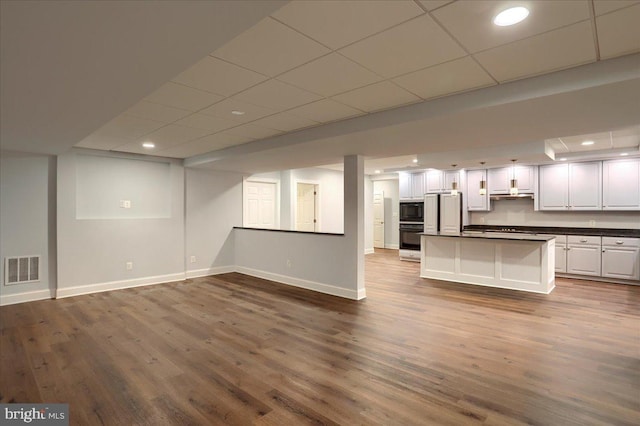 interior space featuring recessed lighting, visible vents, dark wood-type flooring, a drop ceiling, and baseboards