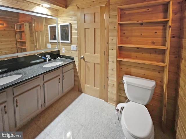 bathroom with vanity, toilet, and wooden walls