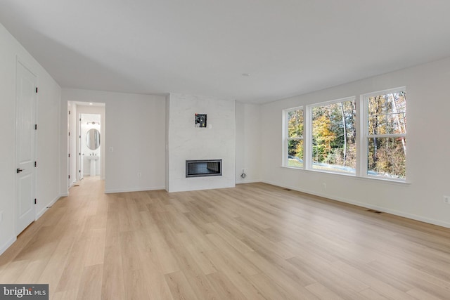 unfurnished living room featuring light wood-type flooring and a large fireplace