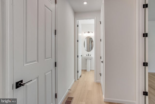 hallway with light wood-type flooring and sink