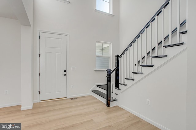 foyer entrance with a high ceiling and light hardwood / wood-style flooring