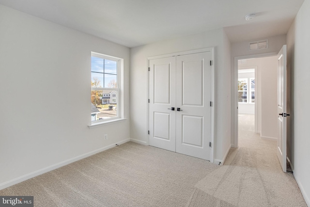 unfurnished bedroom with light colored carpet and a closet