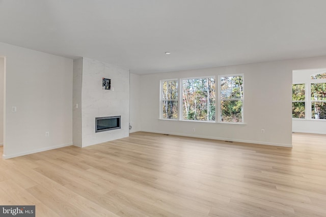 unfurnished living room featuring a high end fireplace and light wood-type flooring