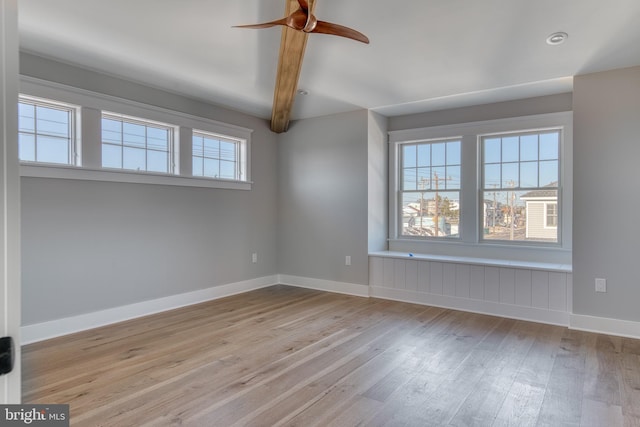 unfurnished room featuring beamed ceiling, ceiling fan, and light hardwood / wood-style flooring