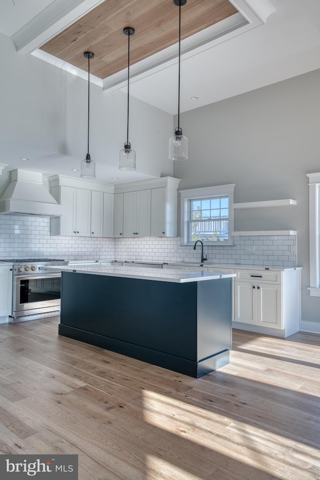 kitchen with custom exhaust hood, decorative backsplash, white cabinetry, and hanging light fixtures