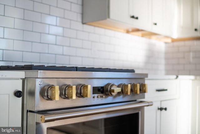 room details with white cabinets, decorative backsplash, and stainless steel range