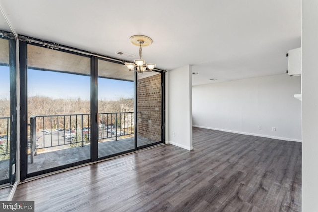 unfurnished room with dark hardwood / wood-style floors, an inviting chandelier, and expansive windows