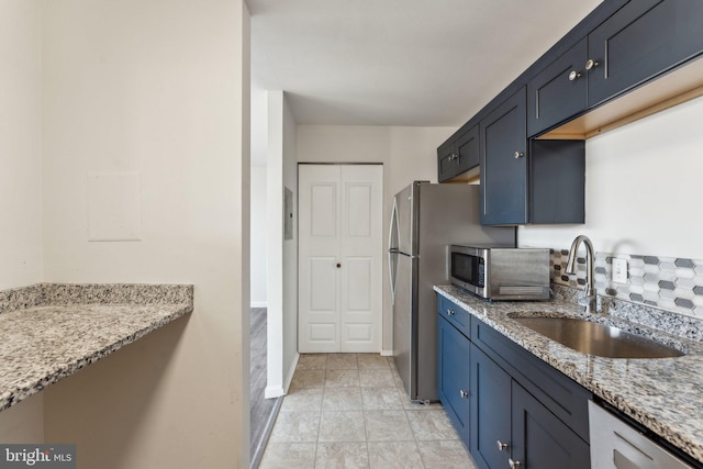 kitchen featuring blue cabinetry, light stone counters, sink, and appliances with stainless steel finishes