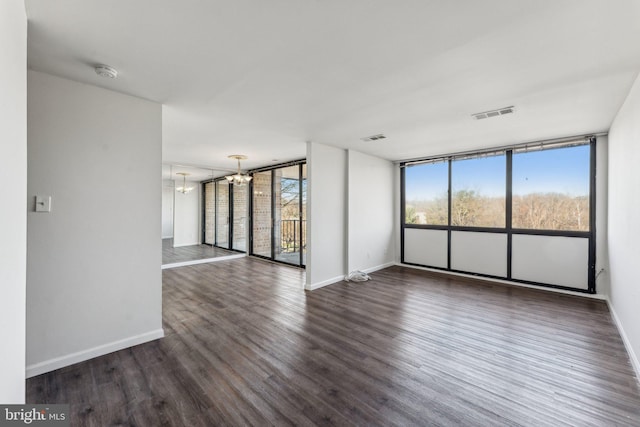 spare room featuring dark hardwood / wood-style floors and an inviting chandelier