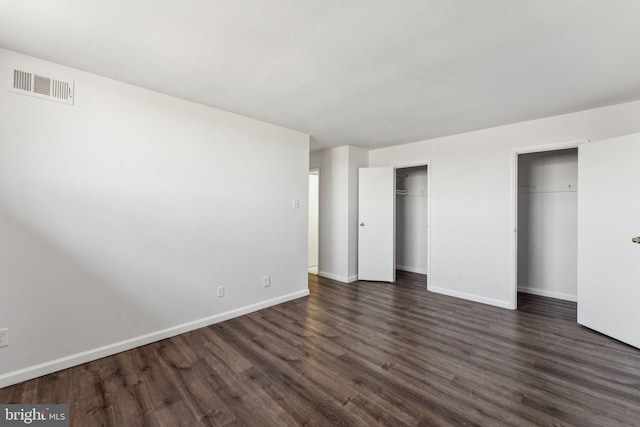 unfurnished bedroom with multiple closets and dark hardwood / wood-style flooring