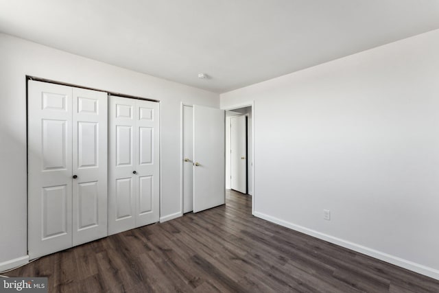 unfurnished bedroom with a closet and dark wood-type flooring