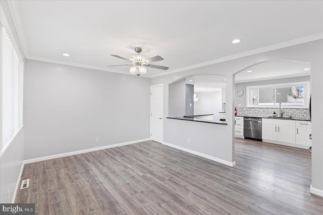 unfurnished living room featuring hardwood / wood-style floors, crown molding, sink, and ceiling fan