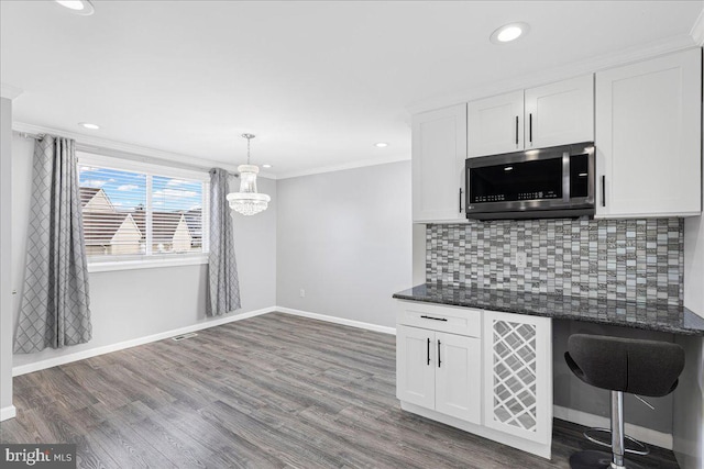 kitchen featuring dark wood-type flooring, crown molding, decorative light fixtures, decorative backsplash, and white cabinets