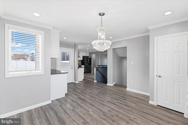 kitchen featuring white cabinetry, hanging light fixtures, black refrigerator, dark hardwood / wood-style floors, and ornamental molding