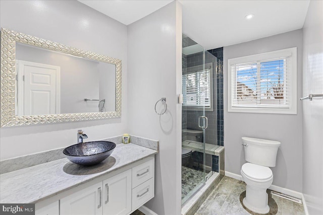 bathroom featuring an enclosed shower, vanity, tile patterned floors, and toilet