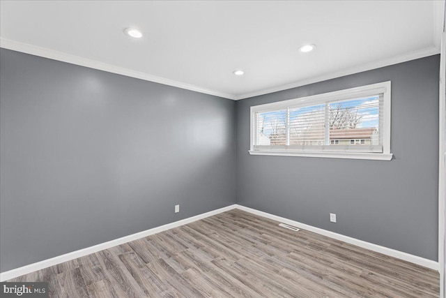 empty room with crown molding and light wood-type flooring