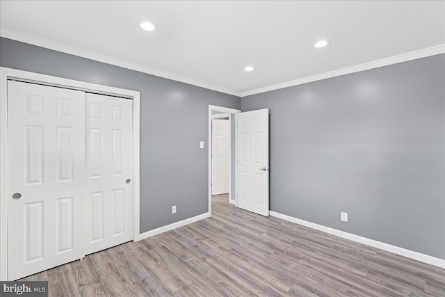 unfurnished bedroom with crown molding, light wood-type flooring, and a closet