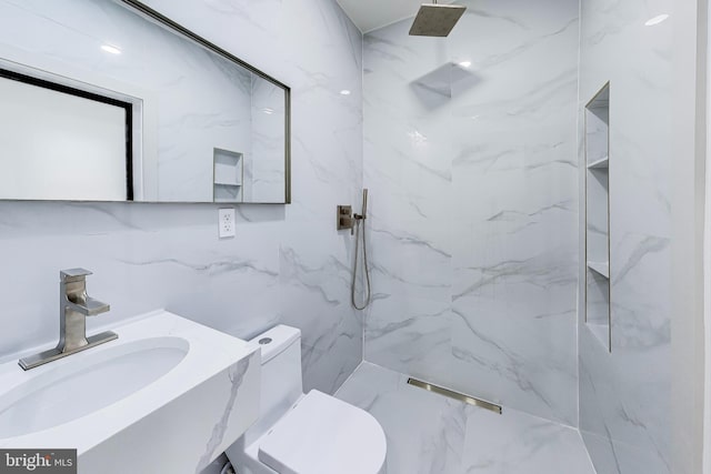 bathroom featuring vanity, toilet, tiled shower, and tile walls