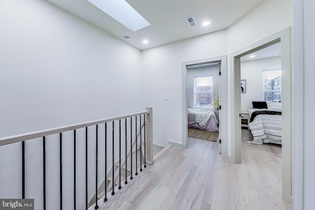 hallway featuring a skylight and light hardwood / wood-style floors