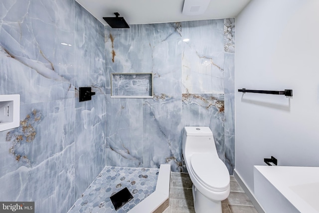 bathroom featuring a tile shower, tile walls, and toilet