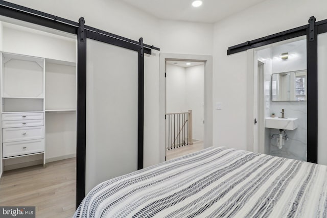 bedroom with connected bathroom, sink, a closet, and light hardwood / wood-style flooring