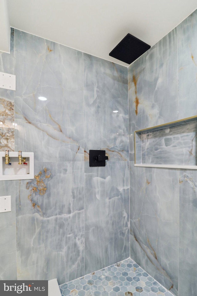 bathroom with tiled shower and tile walls