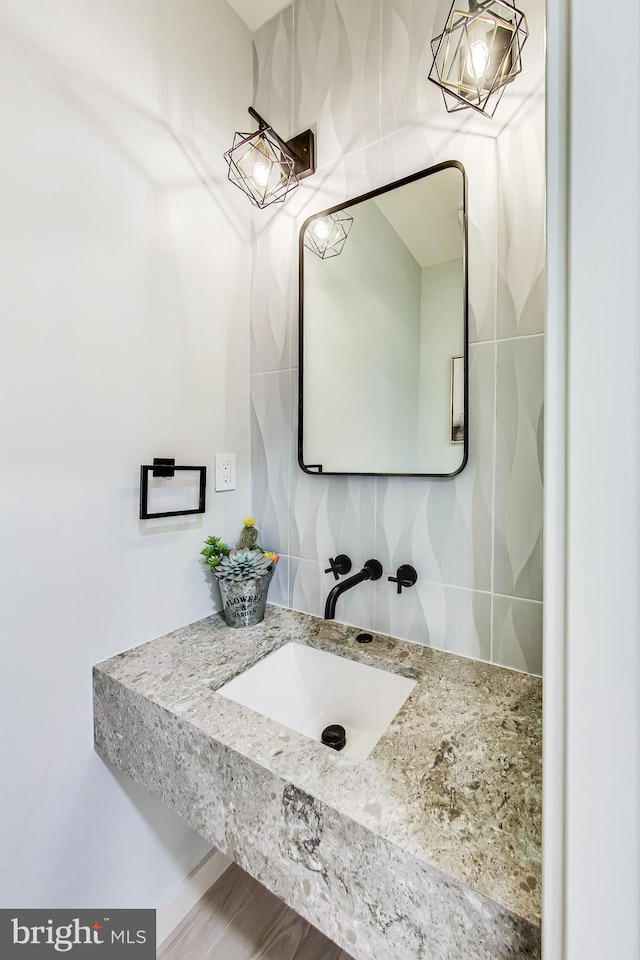 bathroom with wood-type flooring, tasteful backsplash, and sink