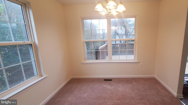 carpeted empty room featuring a chandelier