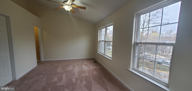 carpeted spare room featuring ceiling fan, plenty of natural light, and lofted ceiling