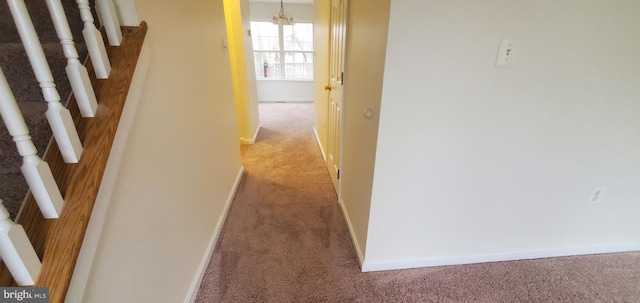 hallway with carpet flooring and a chandelier