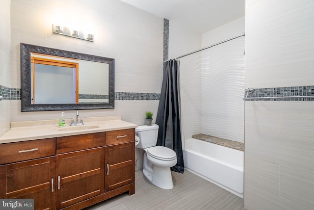 full bathroom with tile patterned floors, toilet, shower / bath combo with shower curtain, vanity, and tile walls