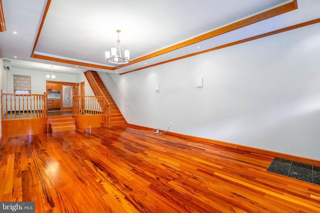 interior space with a chandelier, light wood-type flooring, a tray ceiling, and ornamental molding