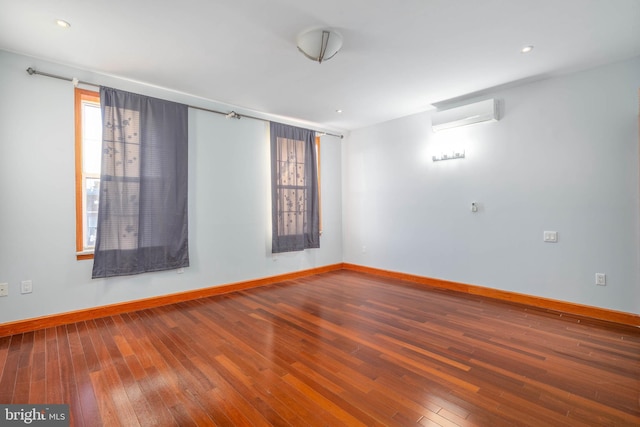 empty room with a wealth of natural light, wood-type flooring, and a wall mounted air conditioner