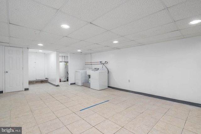 basement with a paneled ceiling, water heater, and independent washer and dryer