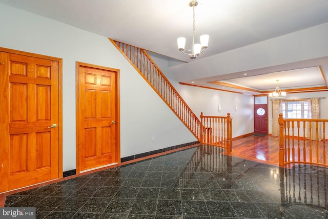 staircase featuring a tray ceiling, crown molding, hardwood / wood-style flooring, and a notable chandelier