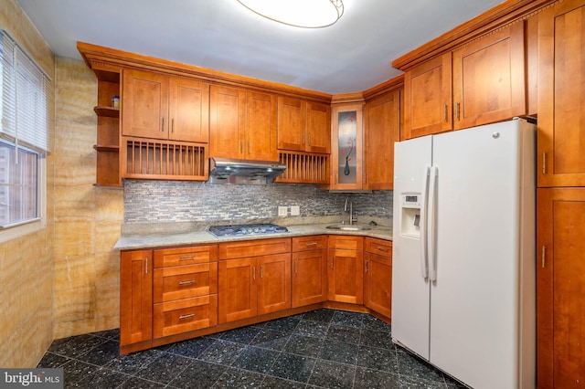 kitchen with stainless steel gas cooktop, light stone counters, white fridge with ice dispenser, and sink