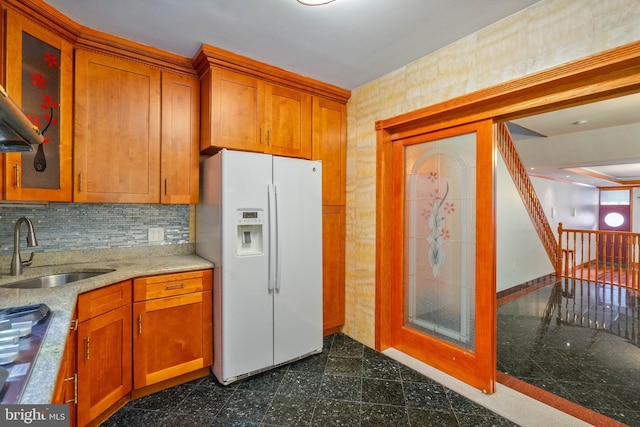 kitchen featuring backsplash, sink, and white refrigerator with ice dispenser