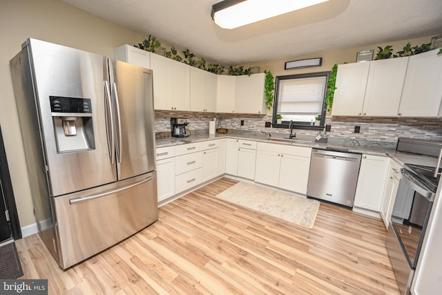 kitchen with white cabinetry, sink, light hardwood / wood-style floors, and appliances with stainless steel finishes